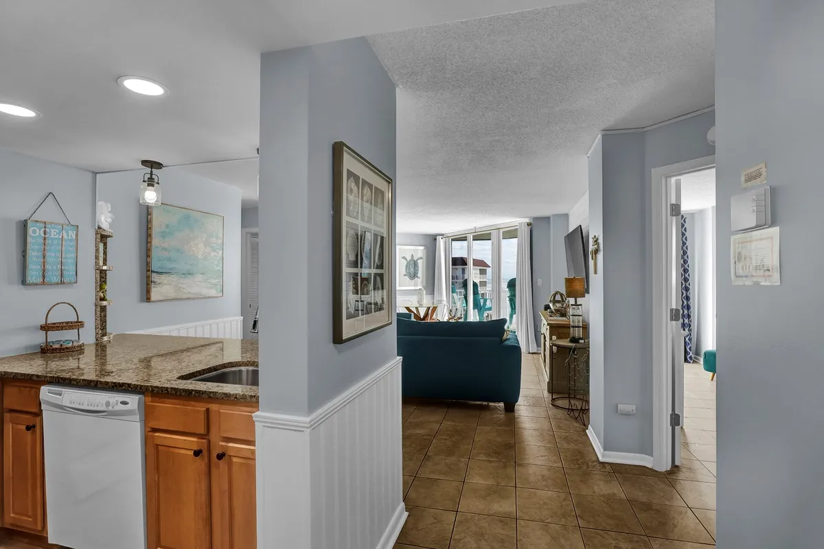 An open-concept interior featuring a well-appointed kitchen island, adjacent living room seating, and large windows that offer panoramic ocean views. The layout encourages cooking, socializing, and unwinding, all while enjoying the natural beauty outside.
