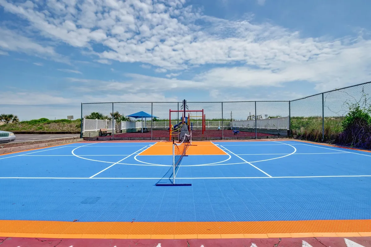 A lively outdoor area featuring a brightly colored basketball court and a modern playground set against an open sky. The scene encourages family play, sports games, and outdoor bonding in a vibrant, active environment.