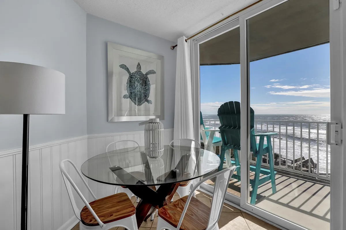 A glass dining table set beside sliding glass doors, offering a direct view of the Atlantic. Turtle artwork and tranquil decor create a relaxed atmosphere, perfect for savoring meals or morning coffee to the sound of waves.