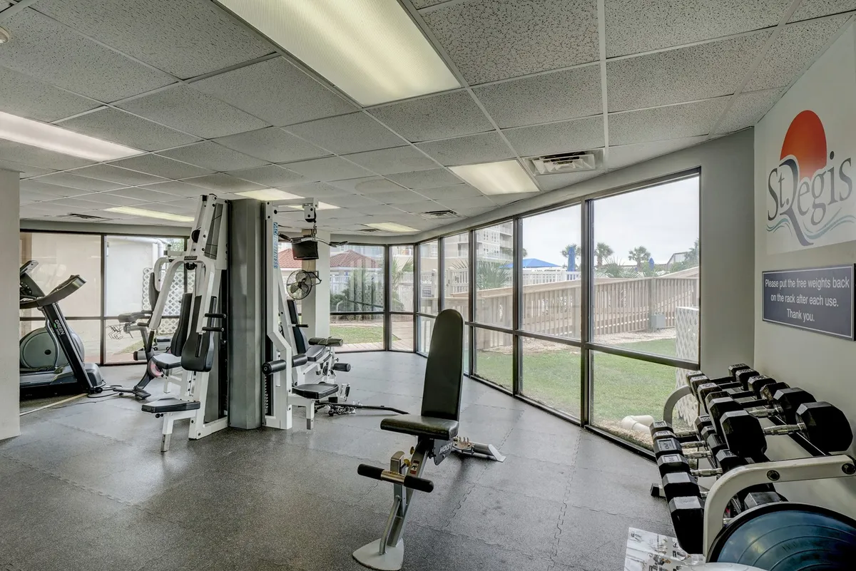 A bright, airy fitness center filled with modern workout equipment beckons guests to maintain their wellness routines. Large windows let in plenty of daylight, energizing the atmosphere and providing glimpses outside, reinforcing the balance between work, wellness, and leisure.